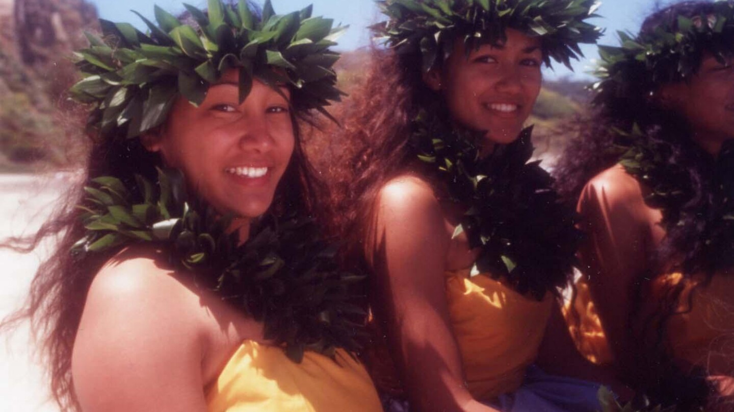 Hula dancers smile into the camera.