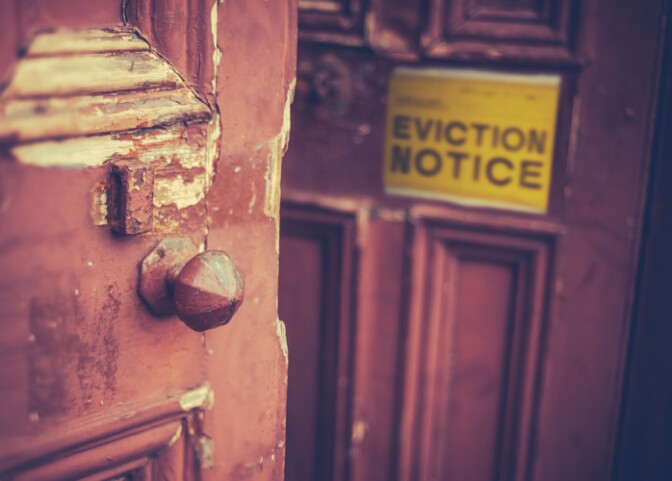 A yellow eviction notice on a brown door.