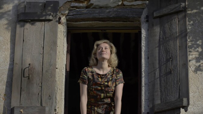A woman at an open window looks up to the sky.
