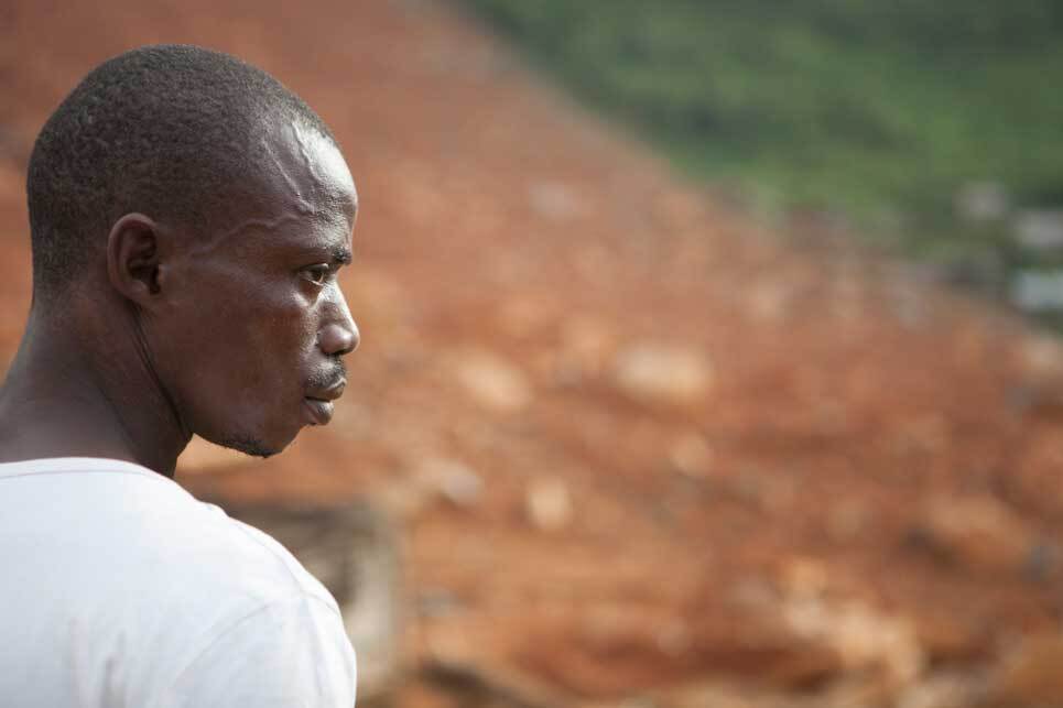 Man looking onto the site of a mudslide that killed and displaced hundreds of people. | Nicky Milne/Thomson Reuters Foundation