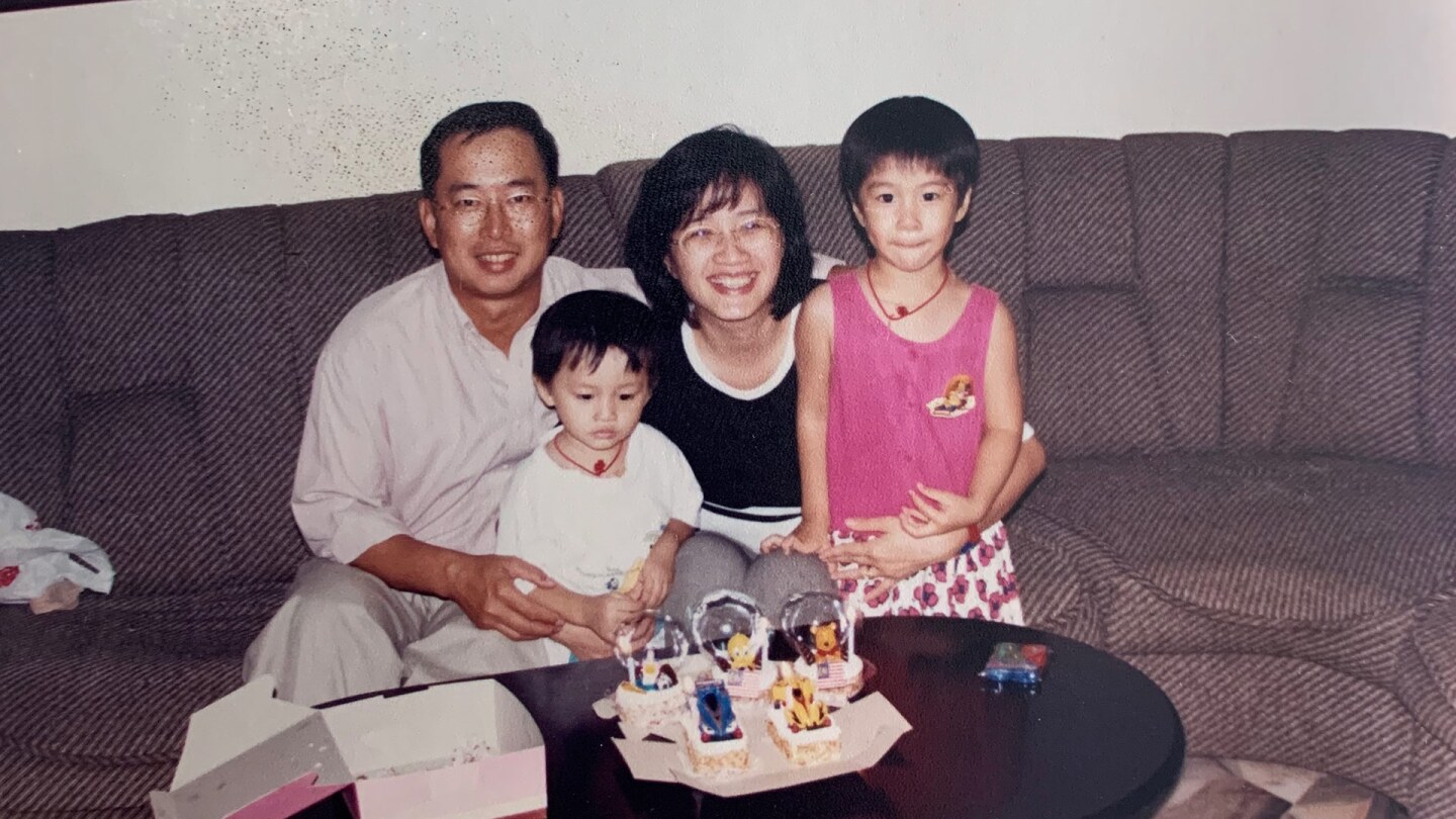 A family, a mother, father and two children, sit on a couch