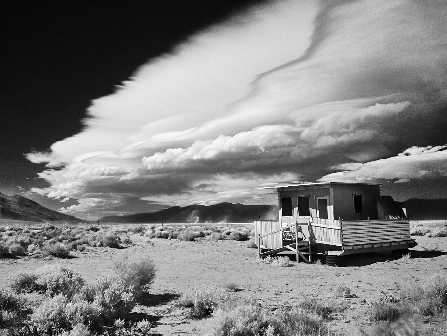 A small wood-paneled house in the middle of the desert in Olancha, California.