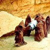Jawas carrying R2-D2 in a desert landscape.