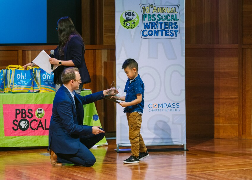 Education reporter Kyle Stokes awards first place to kindergartener Ezra Kim | Courtesy of Mae Koo Photography