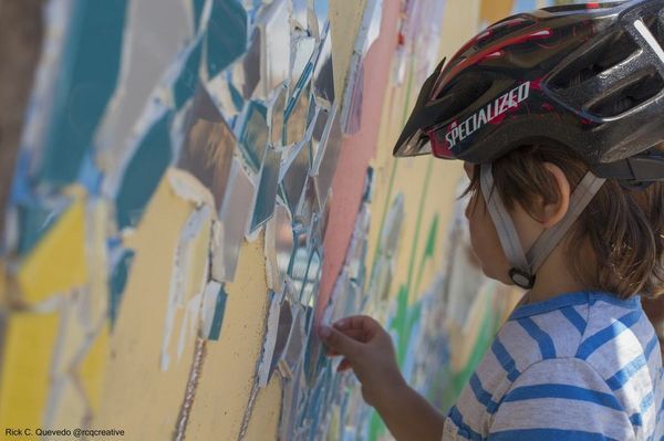 A young bicyclist is one of many who stopped during their ride to add tile to the ARTree tile mosaic mural being installed on South Fork Trail