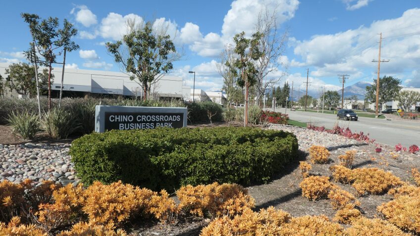 A photo of a sign indicating a warehouse complex with a warehouse in the background