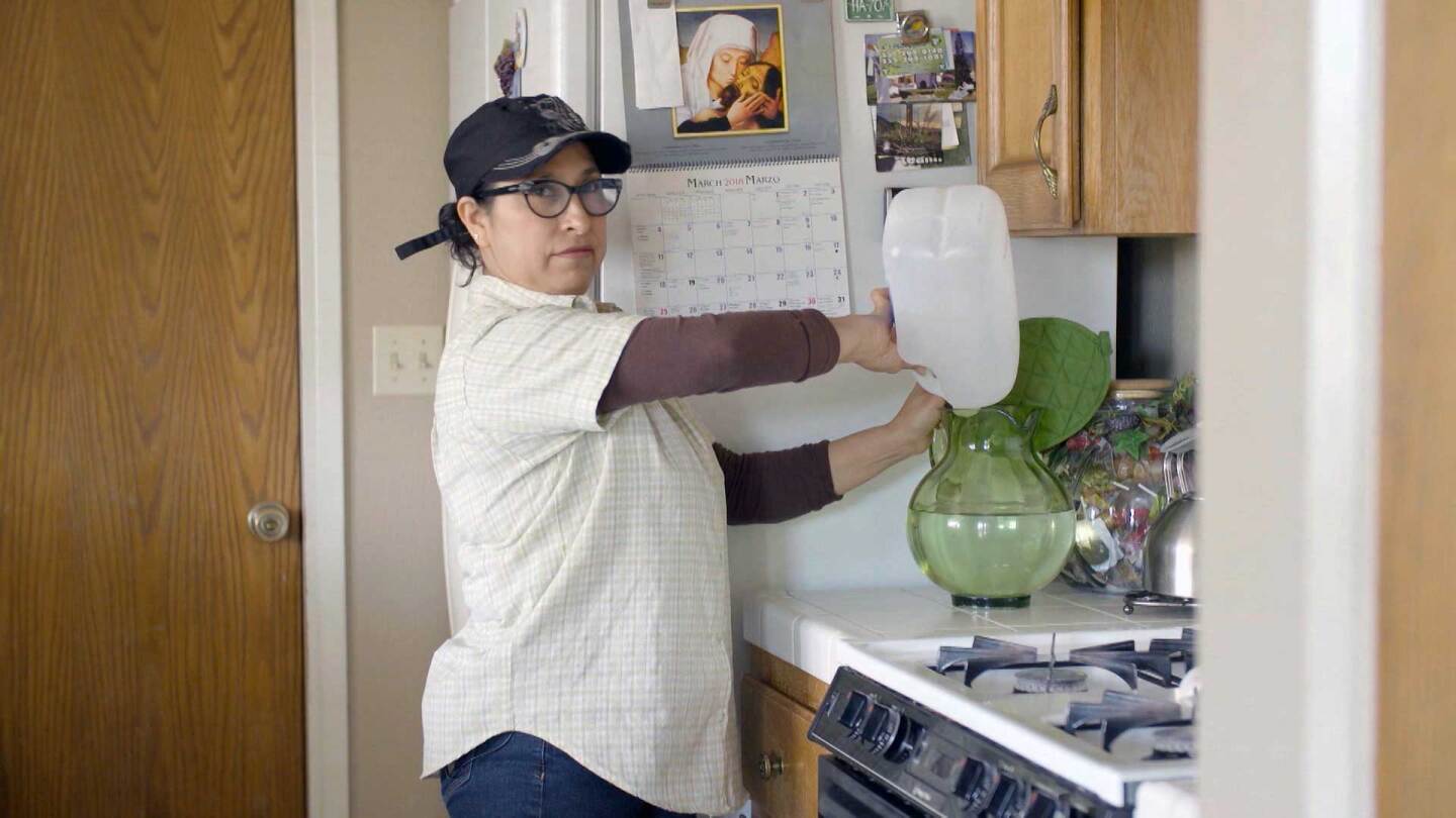 Lanare resident Isabel Solorio demonstrates how she must transfer filtered water for everyday use. | Earth Focus
