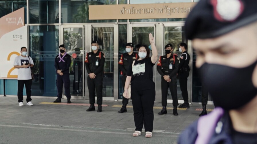 A woman raises her hand with officers standing behind her.
