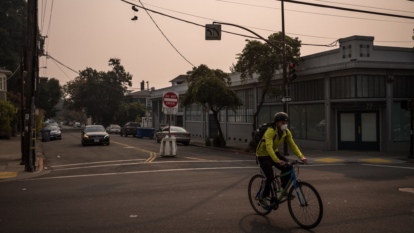 a man rides his bike across an intersection and the air in hazy