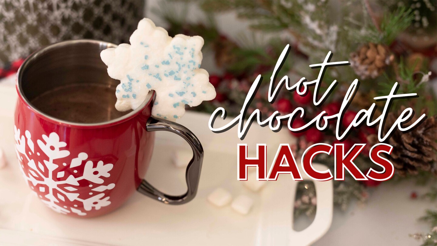 A mug of hot chocolate with a snowflake-shaped cookie wedged on the side.