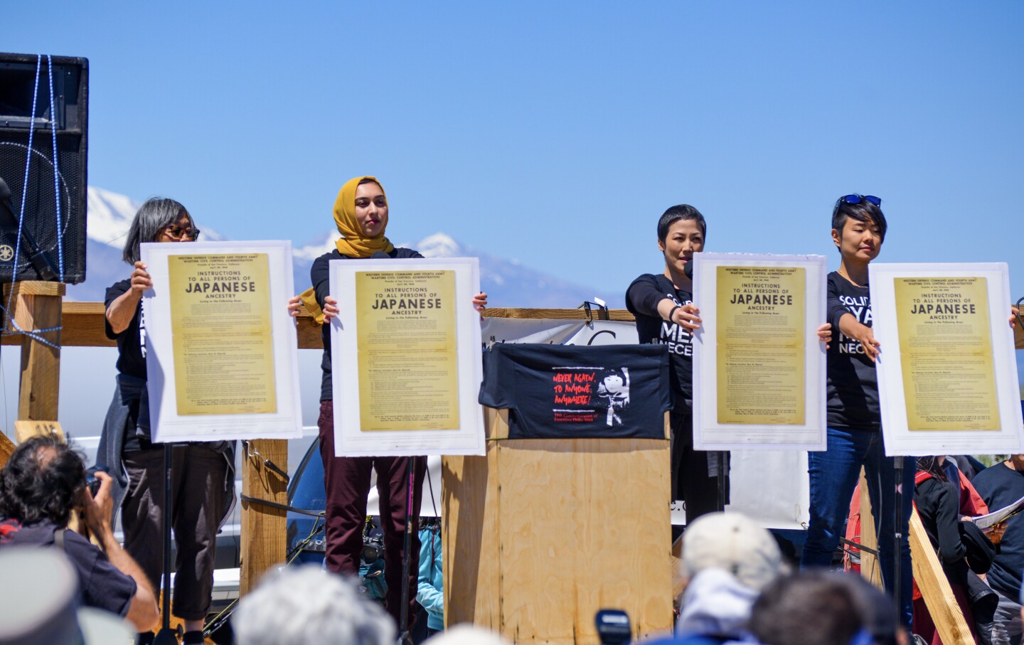 Members of Vigilant Love hold out posters in honor of the Manzanar Cemetery.