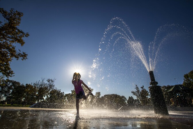 A girl playing in a fountain water at the park