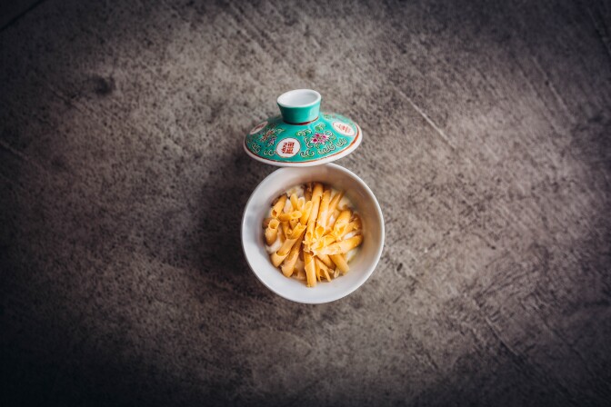 Shaved boniato yam resembling penne pasta sit over a blend of tapioca, fresh cheese and sable, resembling a thick ice cream or cream cheese.