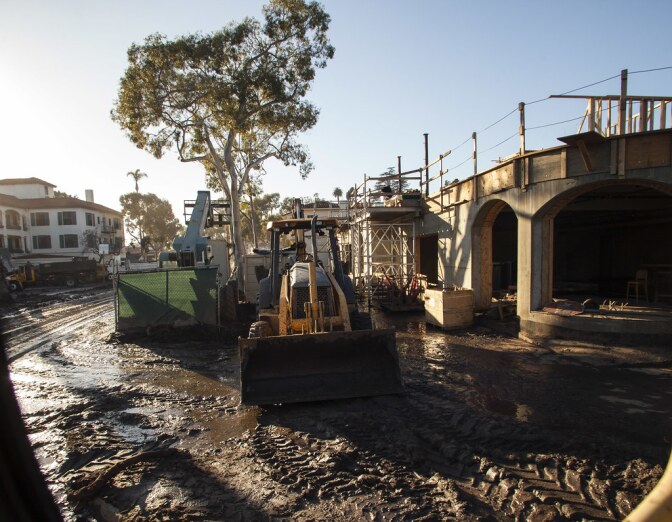 A bulldozer sits atop a thick layer of mud covering roads near a construction site in Montecito, California.
