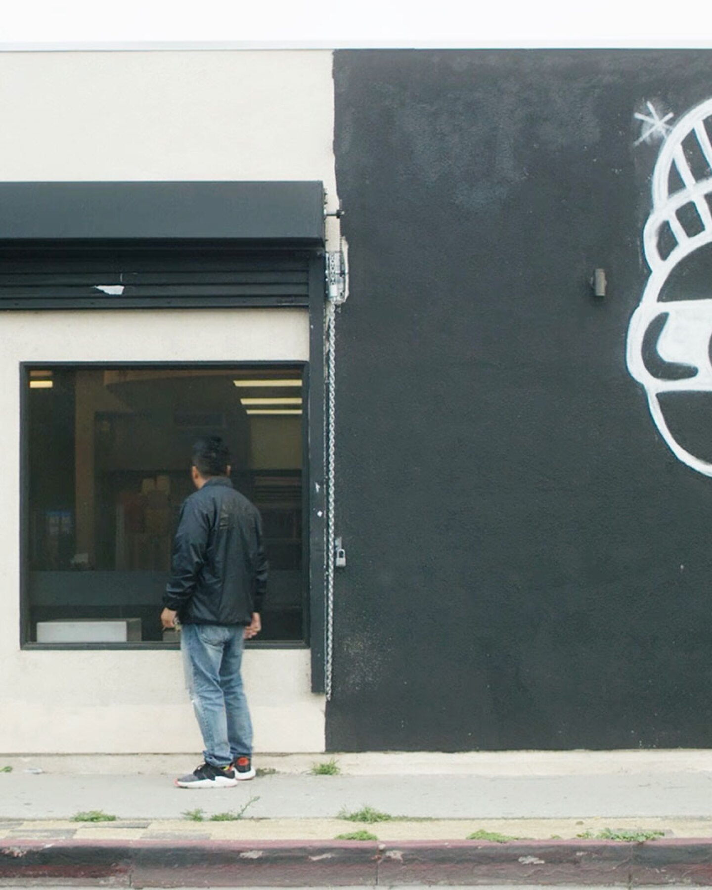 Roy looks into the window of his establishment Locol in Watts. | Still from "Broken Bread"
