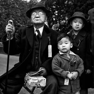 Shigeo “Jerry” Aso, 3, center, and his brother, Sadao “Bill” Asano, 6, with their grandfather, Sakutaro Aso, 70, as they wait for a bus to take them to Tanforan Assembly Center. | Courtesy UC Berkeley Bancroft Library, War Relocation Authority Photographs