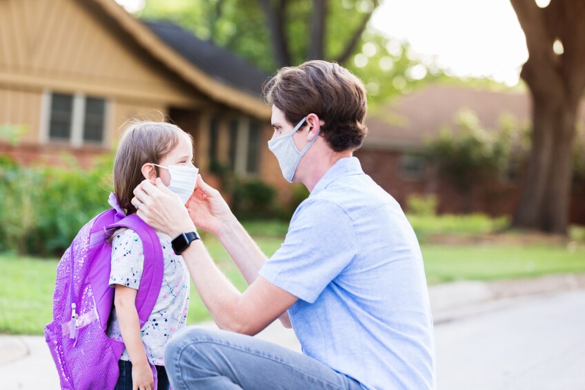 Dad helps daughter with protective mask before school