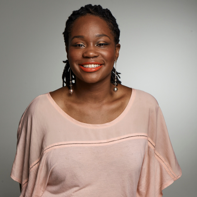 A young African American woman in a peach shirt.