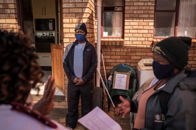Sister Rachel Asitile (61) (L) and Community Healthcare Worker Patricia Galeboe (36) (far right) do a follow up check on Thuso Kalanyane who tested positive for COVID-19. | Thomson Reuters Foundation/Gulshan Khan