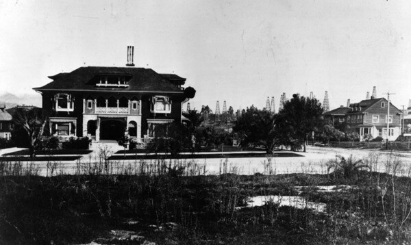 House on Wilshire Boulevard with oil derricks in the background. ca. 1915 | Courtesy of the Los Angeles Public Library