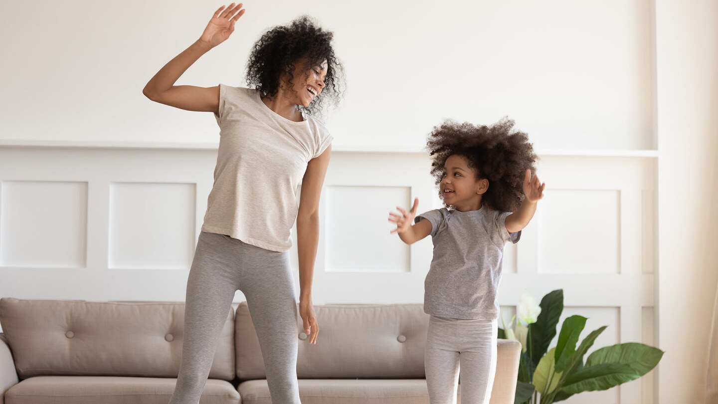 A woman and a little girl jump together as they dance