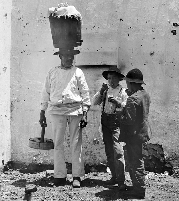 Two boys buy ice cream from vendor Nicolas Martinez, who walked the streets of Sonoratown with his wares on his head. Courtesy of the Title Insurance and Trust / C.C. Pierce Photography Collection, USC Libraries.