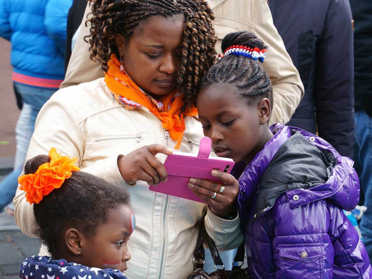 A young girl looks over her caregiver's cell phone.