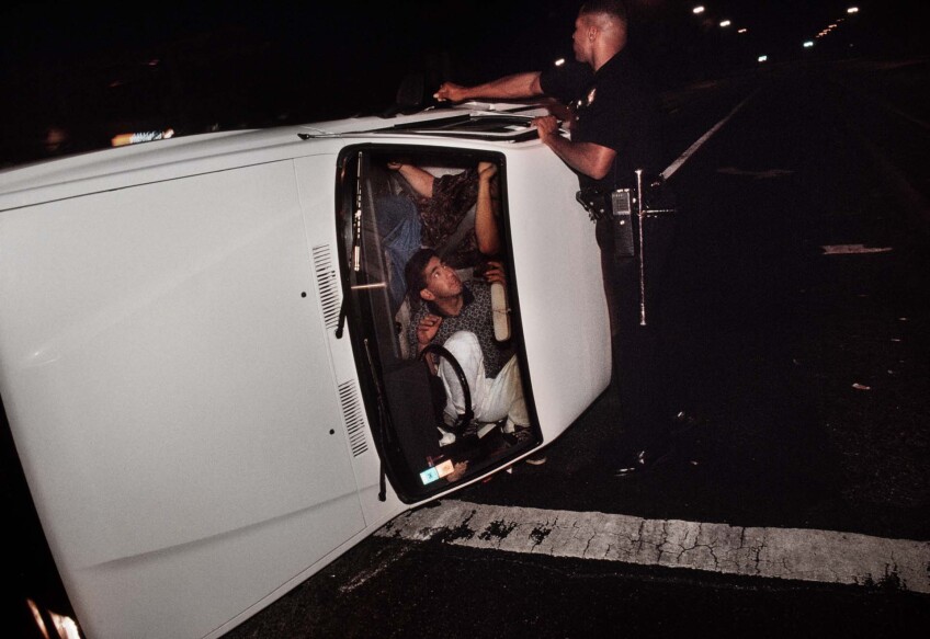 Pacific Division Officer Hoskins tries to pry open the door of a truck involved in a accident that left the driver and passenger locked in the overturned vehicle. | Joseph Rodriguez