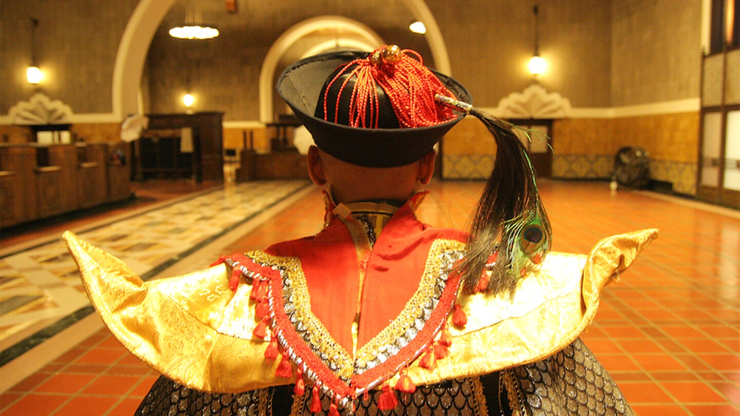A man with an extravagant costume looks out on an empty Los Angeles Union Station.