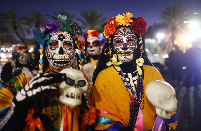 Two of the "Living Muertos" performers dressed as skeletons pose during a nighttime procession.