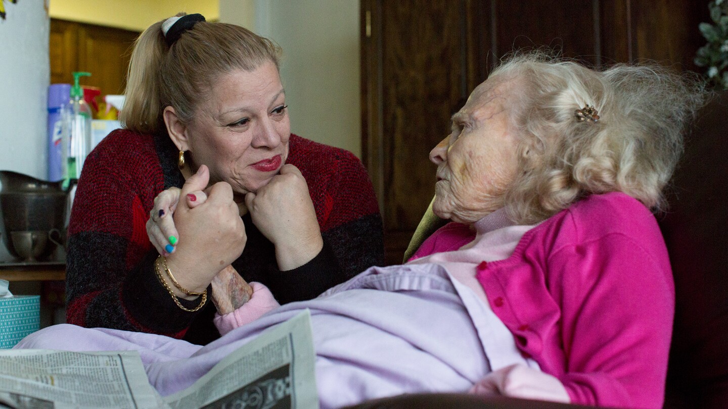 Careworker Vilma Rozen and Dolores Bennett hold hands.