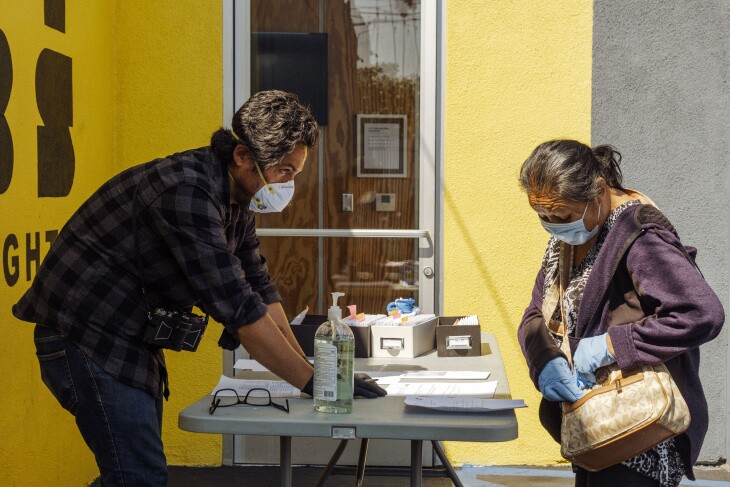 An organizer for the LA Street Vendor Campaign signs in a local street vendor before distributing a cash card containing emergency financial relief. | Chava Sanchez/LAist