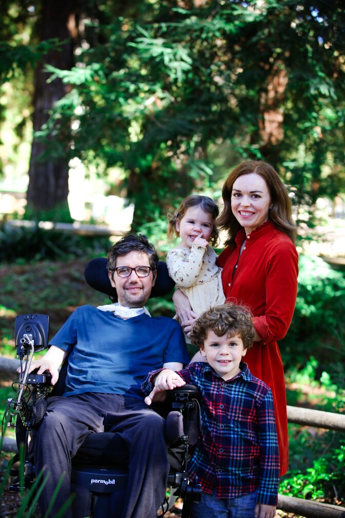 Ady Barkan(left) smiles in a wheelchair while his wife, Rachael King (right), their two children pose for a family photo.