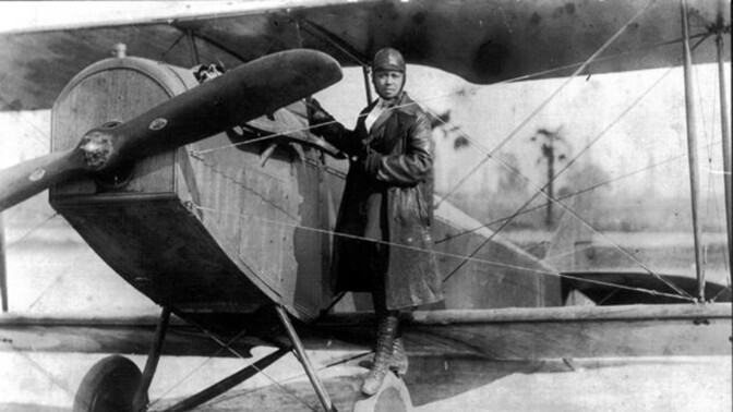 Bessie Coleman, shown here on the wheel of a Curtiss JN-4 “Jennie” in her custom-designed flying suit (circa 1924). | Smithsonian Institution
