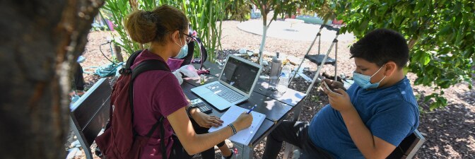 East College Prep High School senior Jocelyn Hernandez follows a remote Advanced Placement (AP) Calculus class as her cousin plays with his phone while sitting in a community garden near her home, August 14, 2020 Boyle Heights. | ROBYN BECK/AFP via Getty