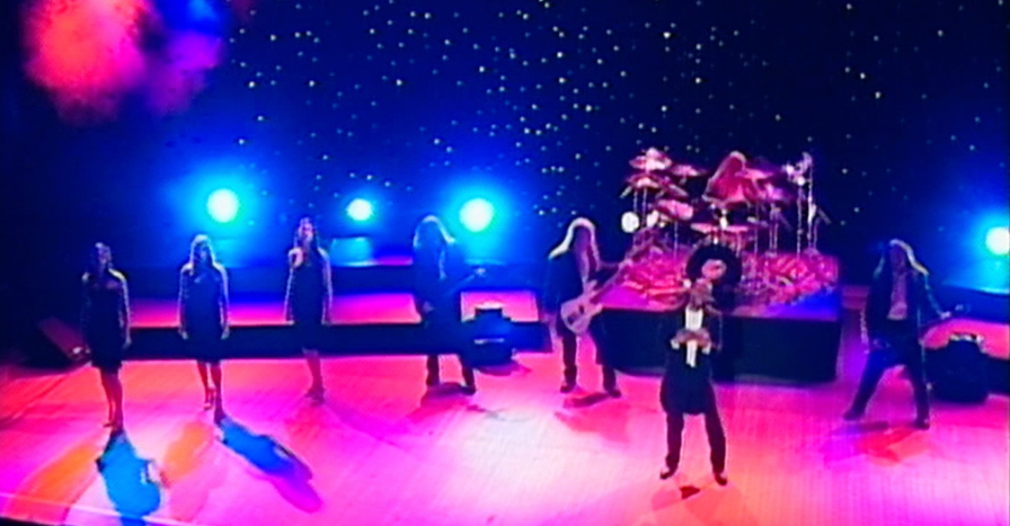 Eight people perform on stage.