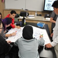 A group gathers around a document for a Climate Action Pathways for Schools class.