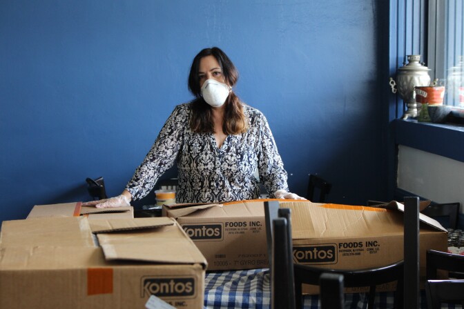 Woman with mask on posing with boxes of food for healthcare workers during COVID-19 outbreak