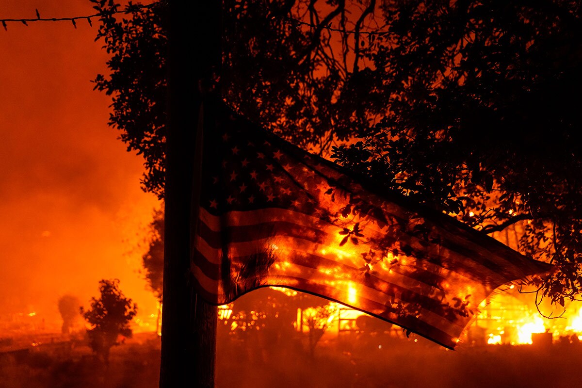 A U.S. Flag flaps in the wind as the Shady Fire impacts structures along CA-12 on Monday, Sept. 28, 2020 in Santa Rosa, California. | Kent Nishimura/Los Angeles Times via Getty Images