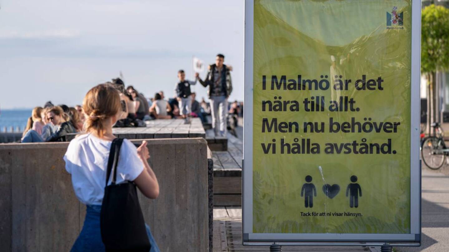 People enjoy the warm evening at Sundspromenaden as the sign reads "In Malmo everything is near. But now we need to keep a distance" in Malmo, Sweden May 26, 2020. TT News Agency/Johan Nilsson via REUTERS