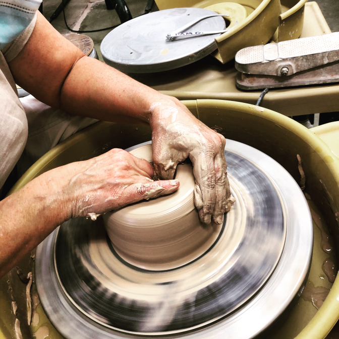 Two hands a centering clay on a potter's wheel.