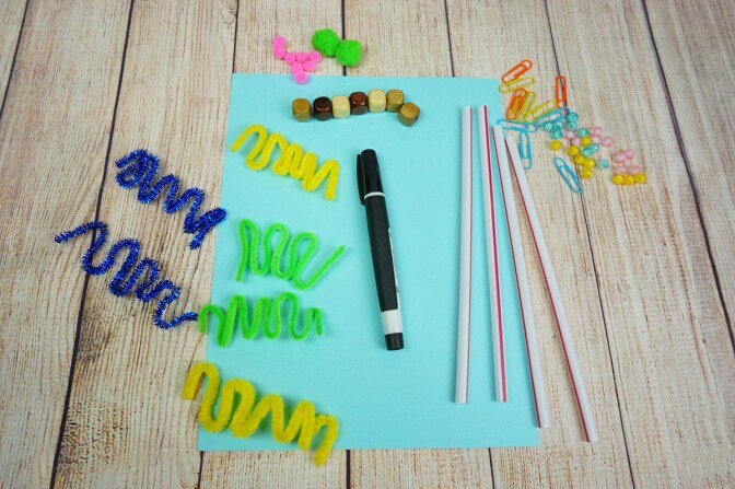 A wooden table with a piece of paper, a marker and small items arranged on top of it.