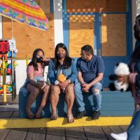 A family wearing masks sits on a bench at the Santa Monica Pier amid the coronavirus pandemic on April 20, 2021 in Los Angeles, California.