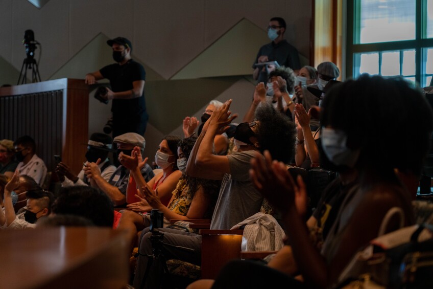 A row of seated and masked audience members applauding in an auditorium at the "A Day of Poetry in LA" event.