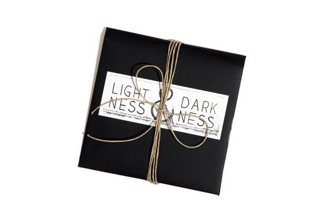 A black CD case has the words "Lightness & Darkness" printed on it. The CD case is bound in twine.
