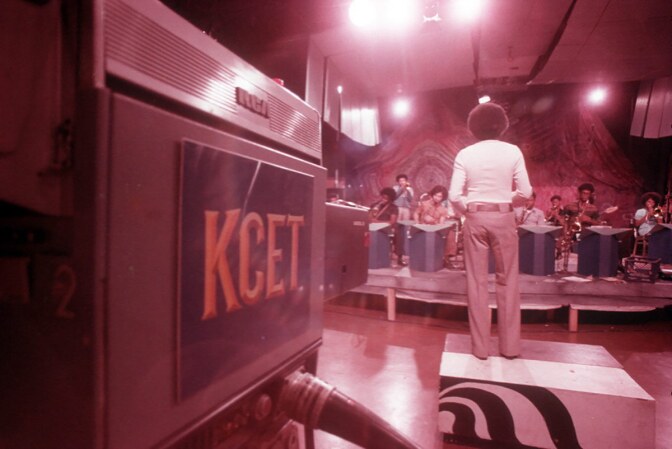 KCET records a performance of the CAA orchestra, led by Troy Robinson, inside The Arena's multi-functional space, with painted murals in the background. | Courtesy of Willie Ford, Jr. and the Compton Communicative Arts Academy Collection, Special Collections and Archives, John F. Kennedy Memorial Library, California State University, Los Angeles