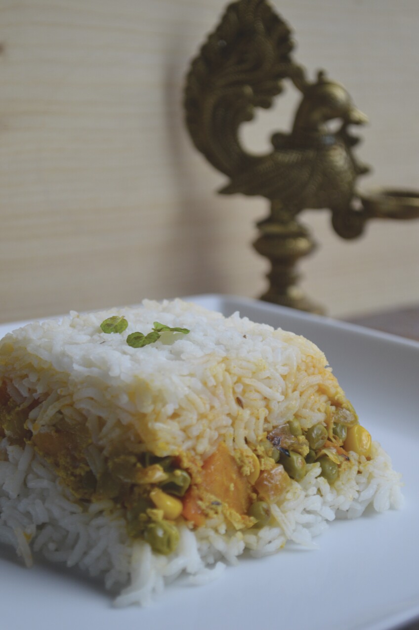 A vegetable biryani shaped into a cube on a plate.