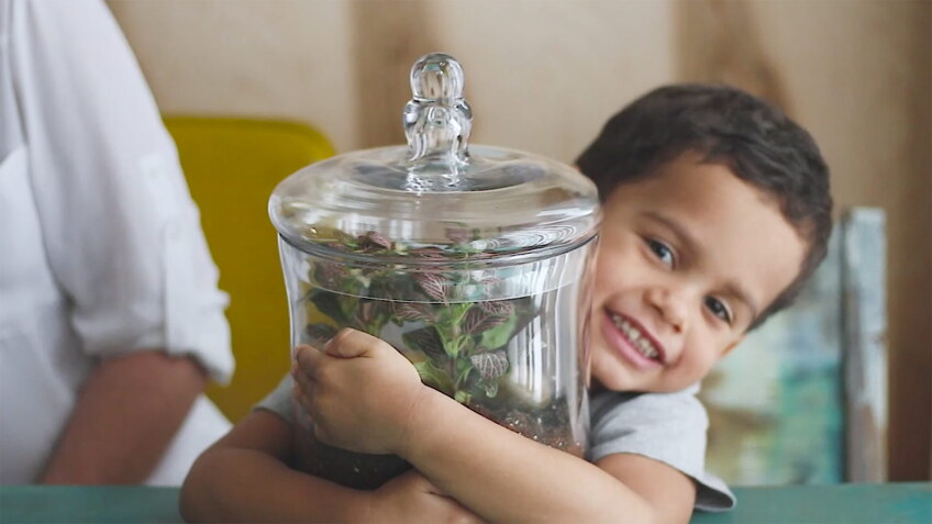 A little boy smiles as he hugs his new terrarium.