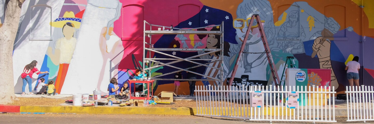 Adults and children working on a new mural.