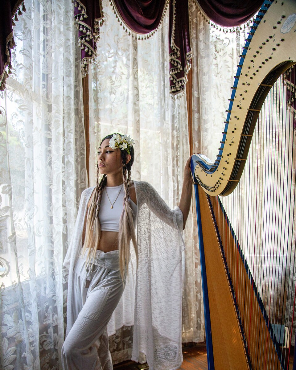 Low Leaf poses next to her harp inside the Perry House at Heritage Square Museum. | Azul Amaral